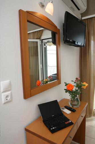 a laptop on a desk in a room with a mirror at Atlon Hotel in Paralia Vrachou