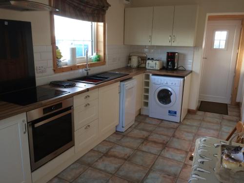 a kitchen with a washing machine and a washer at Harsgeir View Holiday Cottage -Wifi Go green in Breaclete