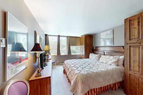 a bedroom with a bed and a desk and windows at Simba Run, Unit 1510 in Vail