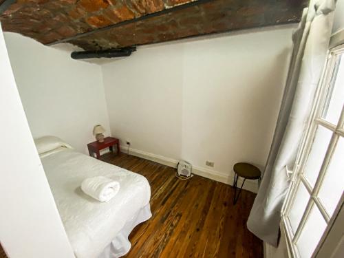 Una pequeña habitación con una cama y una ventana. en Rincón Histórico San Telmo, en Buenos Aires
