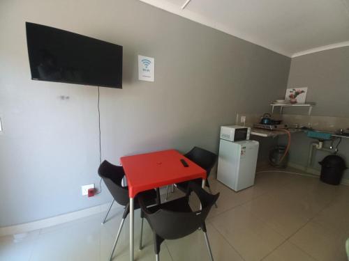 a red table and chairs in a room with a television at Rocky Hills Guesthouse in Piet Retief