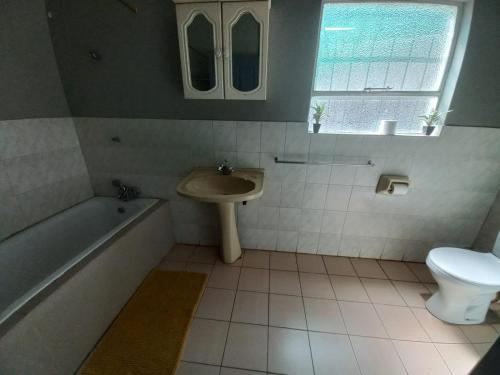 a bathroom with a sink and a tub and a toilet at Rocky Hills Guesthouse in Piet Retief