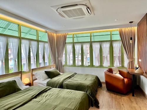 a bedroom with two beds and a chair and windows at The Tangerine Guesthouse in Bangkok