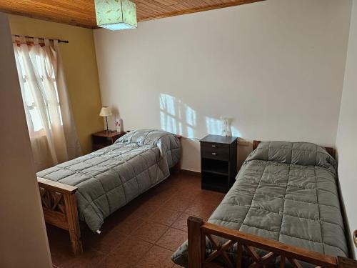 a bedroom with two beds and a desk and a window at La Herradura de Ushuaia in Ushuaia