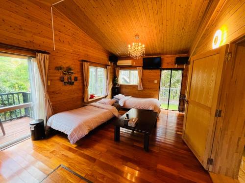 two beds in a room with wooden walls and wood floors at Lodge Crea in Ujimi