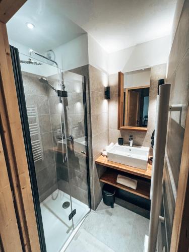 une salle de bain avec un lavabo et une douche dans l'établissement La Mélèzine, Cocon détente avec sauna, au Monêtier-les-Bains