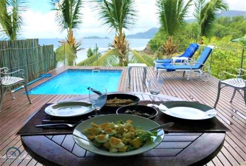 stół z talerzami jedzenia obok basenu w obiekcie South Point Villas Cerf Island w mieście Cerf Island