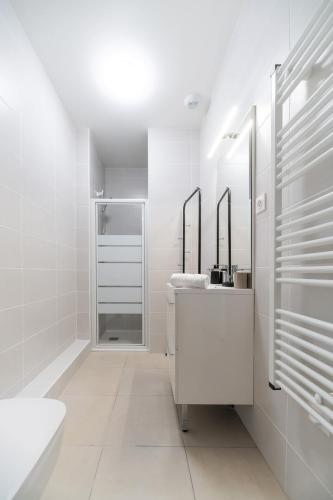 une salle de bain blanche avec un lavabo et un miroir dans l'établissement Le Royal - Appartement design - Hyper centre, à Vichy