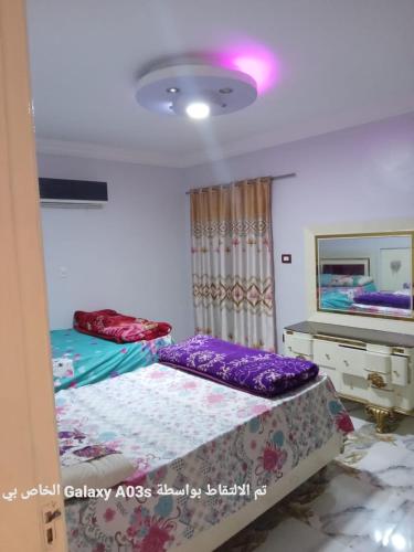 1 dormitorio con 2 camas individuales y TV en الاسكندريه en Al Ḩamīdāt