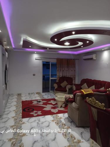 una sala de estar con sofás y un techo con luces moradas. en الاسكندريه en Al Ḩamīdāt