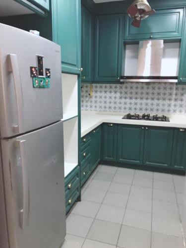 a kitchen with green cabinets and a refrigerator at teratak akilla in Putrajaya
