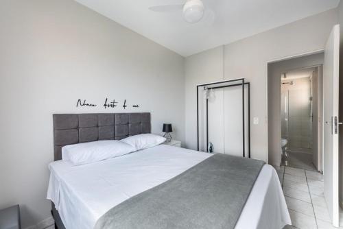 a white bedroom with a large bed and a bathroom at Apartamento Em Santo André 3 Quartos e Garagem | Camilópolis in Santo André