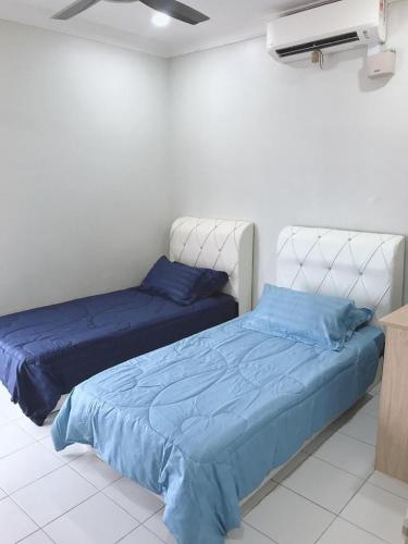 two beds in a bedroom with blue sheets at teratak akilla in Putrajaya