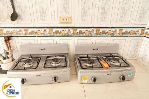 duas placas de fogão numa cozinha com armários brancos em KOMODO ALOJAMIENTO- hostal autoservicio - ubicado muy cerca al centro histórico -Habitaciones con baño privado, wifi , cama 2x2 em Popayán