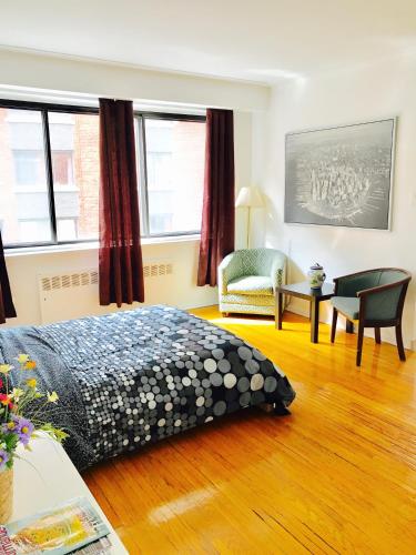 - une chambre avec un lit, une chaise et des fenêtres dans l'établissement Stylish Montreal Apartment: Comfortable Stay in the Golden Square Mile, à Montréal