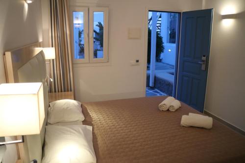 a room with a white bed and a blue door at Petinaros Hotel in Mikonos