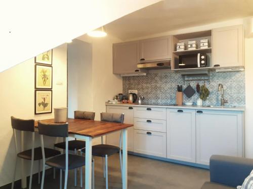 una cocina con armarios blancos y una mesa y sillas de madera. en Alloggio Torino InQuadro en Turín