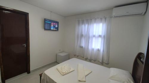 a small room with a bed with two towels on it at Pousada Kasarão Praia Grande Ubatuba in Ubatuba