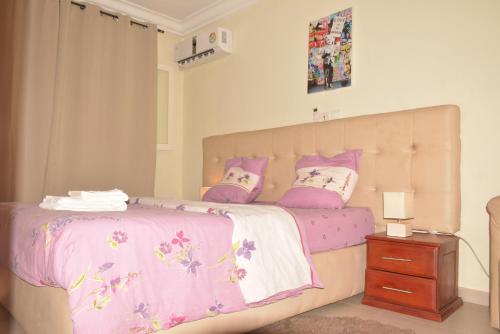 a bedroom with a bed with pink and white sheets and pillows at Polgaro duplex luxueux in Douala