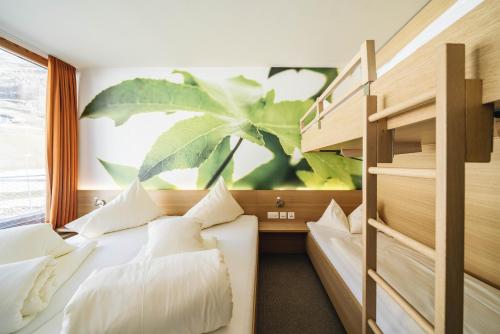1 dormitorio con 2 camas y una planta en la pared en Smart-Hotel, en Samnaun