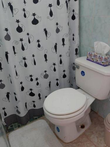 a bathroom with a toilet with a black and white shower curtain at Cozy 1 br 1 bath apartment with free parking in Penonomé