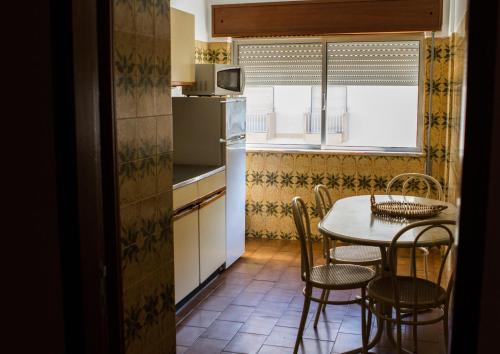 a kitchen with a table and chairs and a kitchen with a window at Columbia Apartamentos Turisticos in Portimão