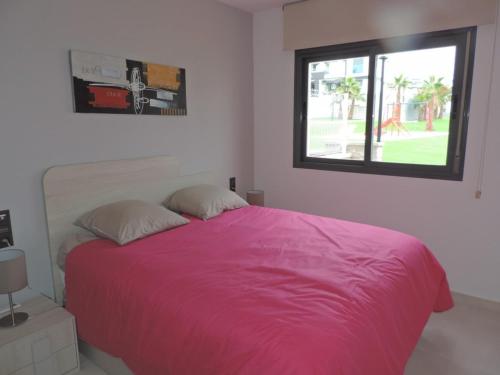 um quarto com uma grande cama rosa e uma janela em Oasis Beach VIII Punta Prima 3023 em Torrevieja