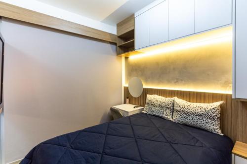 um quarto com uma cama preta e uma parede branca em Vista Alta-23ºandar/Academia/Insper e Hosp.São Luiz 650mts/Pq.Ibirapuera 1Km/ WiFi 257Mbps em São Paulo