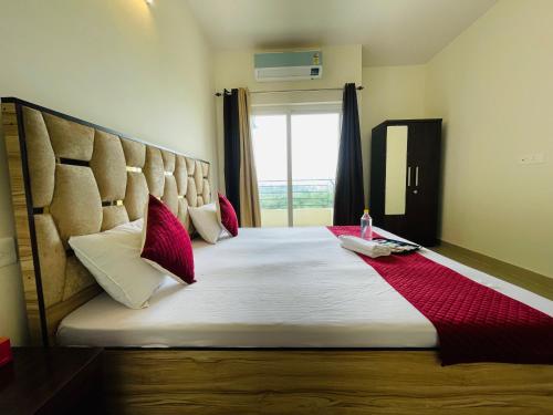 una camera da letto con un letto grande con cuscini rossi di Atulyam Stays Sushant Golf City a Lucknow