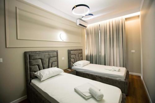 duas camas num quarto de hotel com lençóis brancos em Luxury Apartment at Condor Center em Tirana