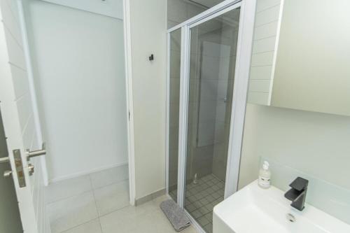 a white bathroom with a shower and a sink at Ocean Glimpse Bellamare in Summerstrand