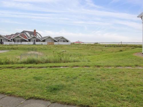 a house on a grassy hill with houses in the background at Apartment Gertruda - 2-3km from the sea in Western Jutland by Interhome in Havneby