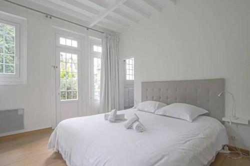 - une chambre blanche avec un grand lit blanc et des oreillers blancs dans l'établissement Maison ensoleillée centre de deauville, à Deauville