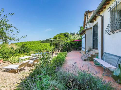 a patio with benches and an umbrella next to a building at Holiday Home Ridaldi by Interhome in Greve in Chianti