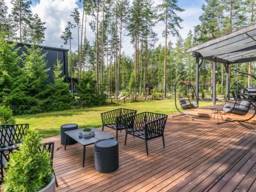 een houten terras met stoelen en een speeltuin bij Holiday Home Villa murdoc by Interhome in Vierumäki