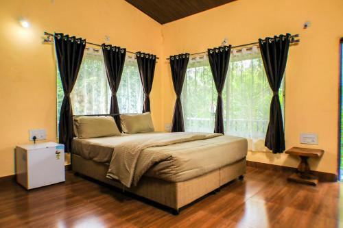 a bedroom with a bed in front of windows at The Kille Torna Resort in Pune