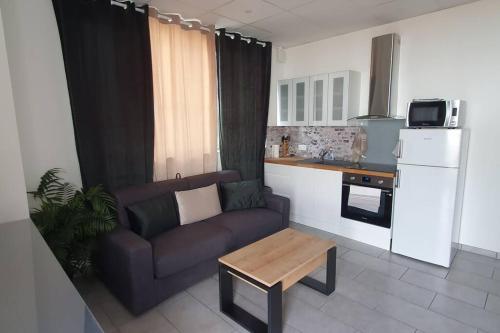 a living room with a couch and a table in a kitchen at Studio Hadda in Lempdes