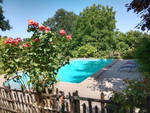 une piscine derrière une clôture avec des roses dans l'établissement Maison Dominique, à Balzac