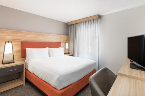 a hotel room with a bed and a flat screen tv at Candlewood Suites Eagan - Mall of America Area by IHG in Eagan