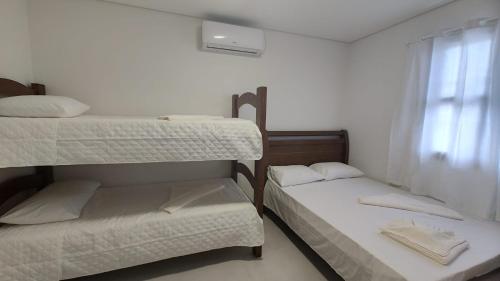 two bunk beds in a room with a window at Pousada Kasarão Praia Grande Ubatuba in Ubatuba