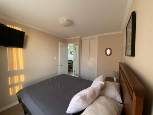 Un dormitorio con una cama con almohadas blancas. en Lindo Departamento en El Tabo, Condominio Vista Mar en El Tabo