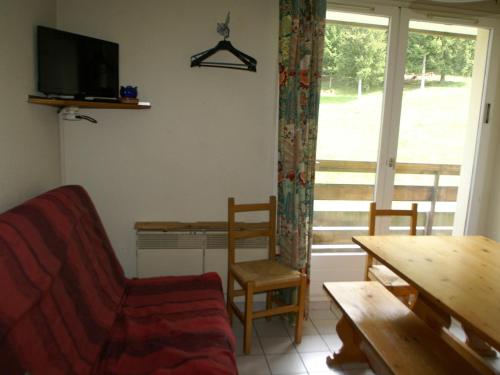 un salon avec un canapé, une table et une fenêtre dans l'établissement 2 pièces au pied des pistes avec balcon et équipements complets - FR-1-557-95, à Les Adrets