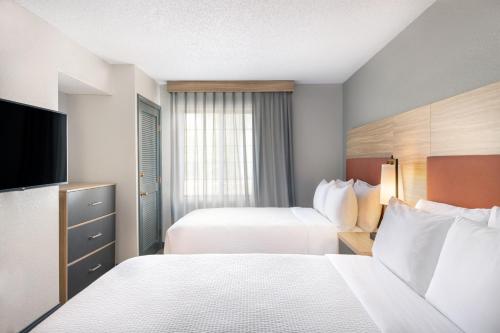 a hotel room with two beds and a flat screen tv at Candlewood Suites Eagan - Mall of America Area by IHG in Eagan