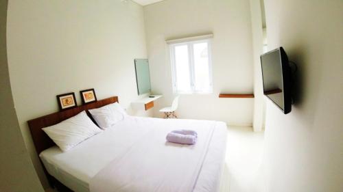 ein Schlafzimmer mit einem weißen Bett und einem lila Handtuch darauf in der Unterkunft Omah Bondi Family Homestay by FH Stay in Yogyakarta