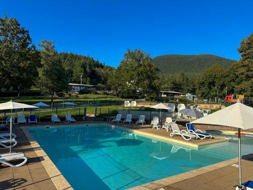 a large swimming pool with chairs and umbrellas at Hôtel parc & spa Les cigognes in Albé