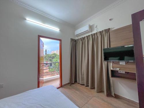 a bedroom with a bed and a tv and a window at Hotel Elite By Agira Hotels-Free Airport Pickup or Drop in Yelahanka