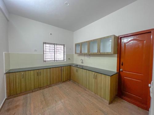 an empty kitchen with wooden cabinets and a red door at Hotel Elite By Agira Hotels-Free Airport Pickup or Drop in Yelahanka