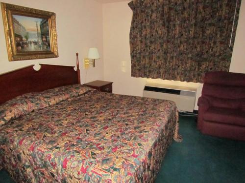 a hotel room with a bed and a chair at Western Inn & Suites Hampton in Hampton