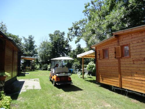 a golf cart parked in a yard next to a cabin at Campeggio Punta di Crabbia in Pettenasco