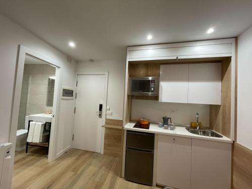 een keuken met witte kasten en een wastafel bij Apartamentos La Solana in Pla de l'Ermita